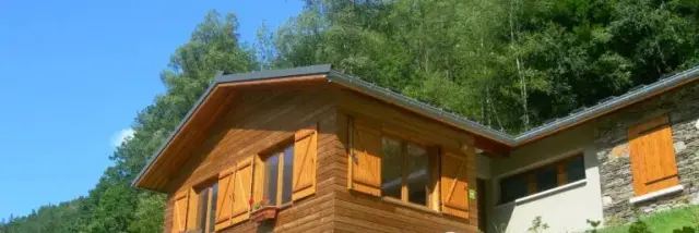 Wooden house with orange shutters on a green hillside