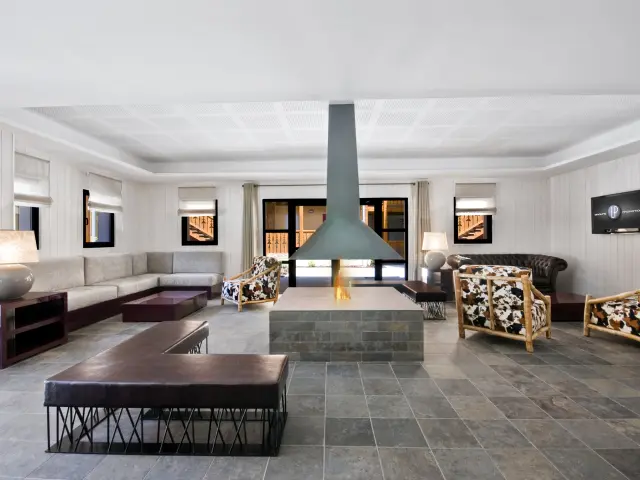 Salon moderne avec cheminée centrale, canapés et fauteuils