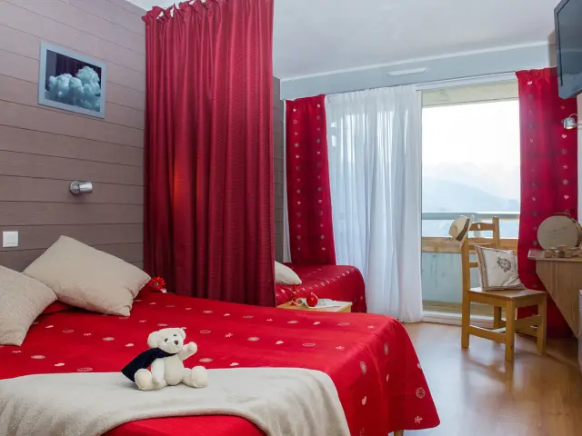 Bedroom with a double red bed, red curtains, mountain view