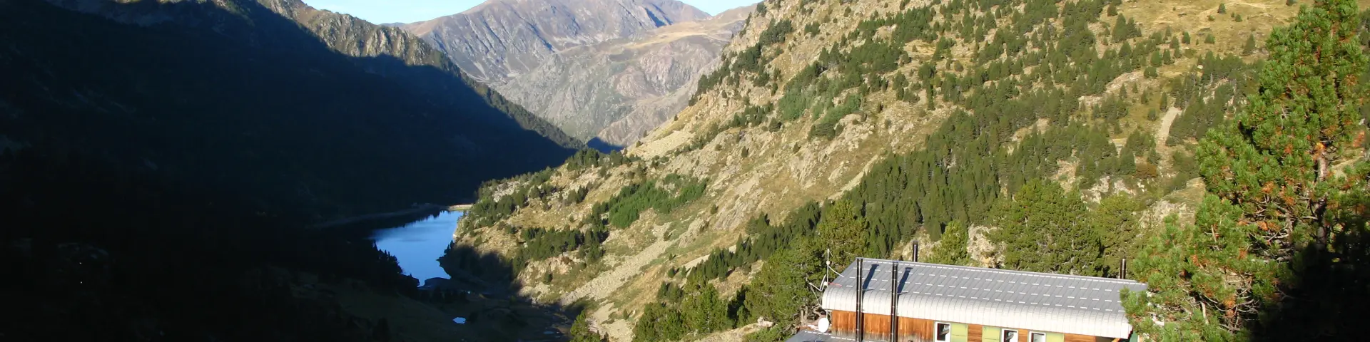 Un refugio de montaña aislado rodeado de paisajes montañosos y un lago