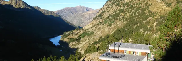 An isolated mountain refuge surrounded by mountainous landscapes and a lake