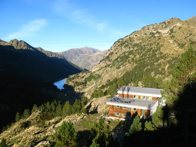 An isolated mountain refuge surrounded by mountainous landscapes and a lake