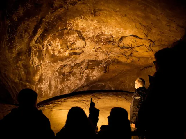 Grupo de personas observando pinturas rupestres en una cueva