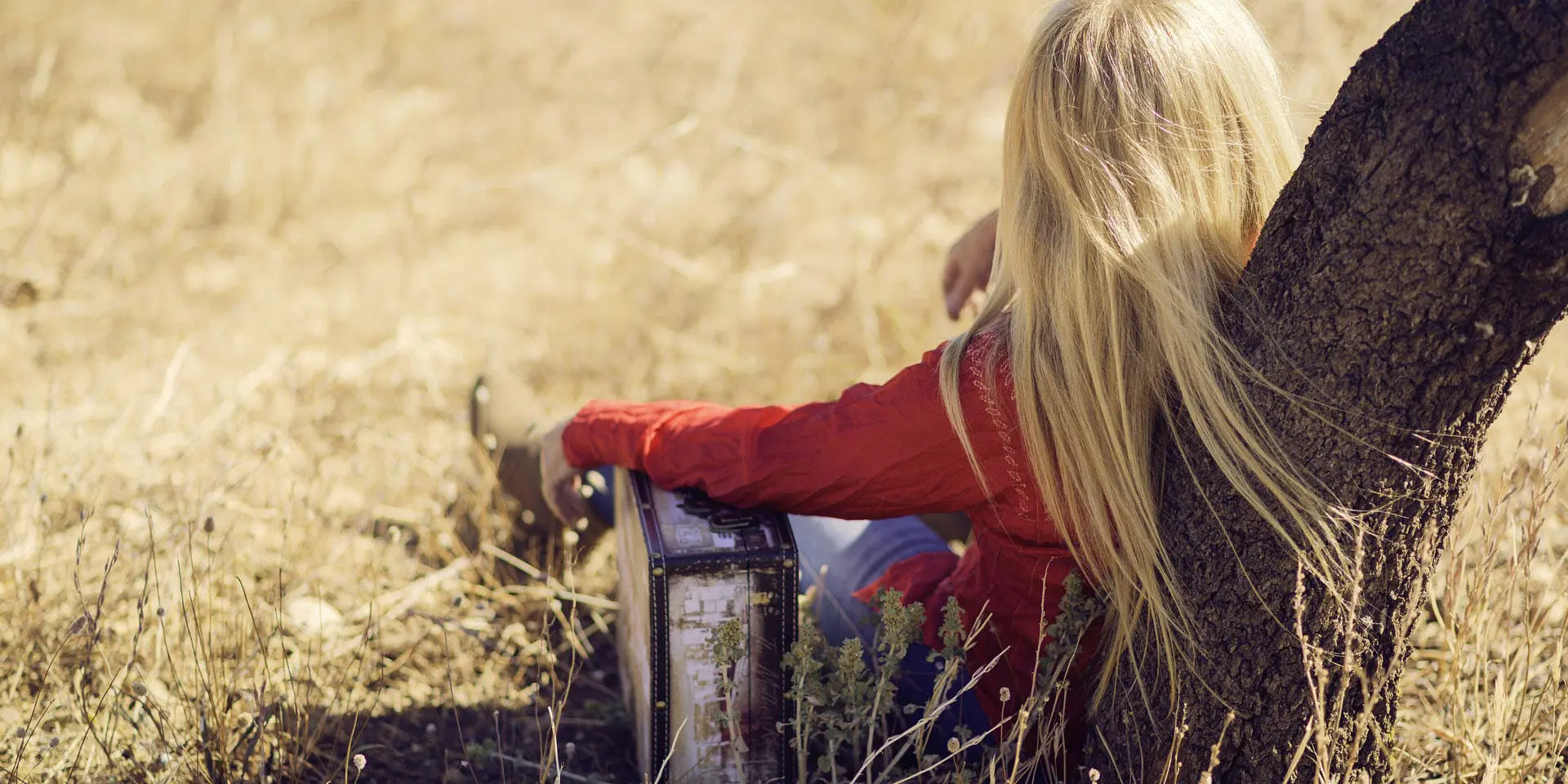 Enfant blond assis dans un champ avec un animal