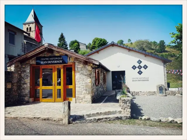 Stone building with an orange wooden door and a sign reading Jean Duvernoy Historical Center