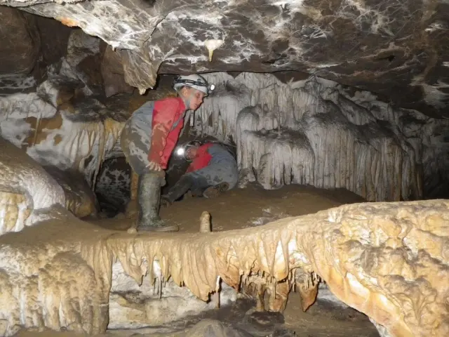 Person exploring a cave with stalactites and stalagmites