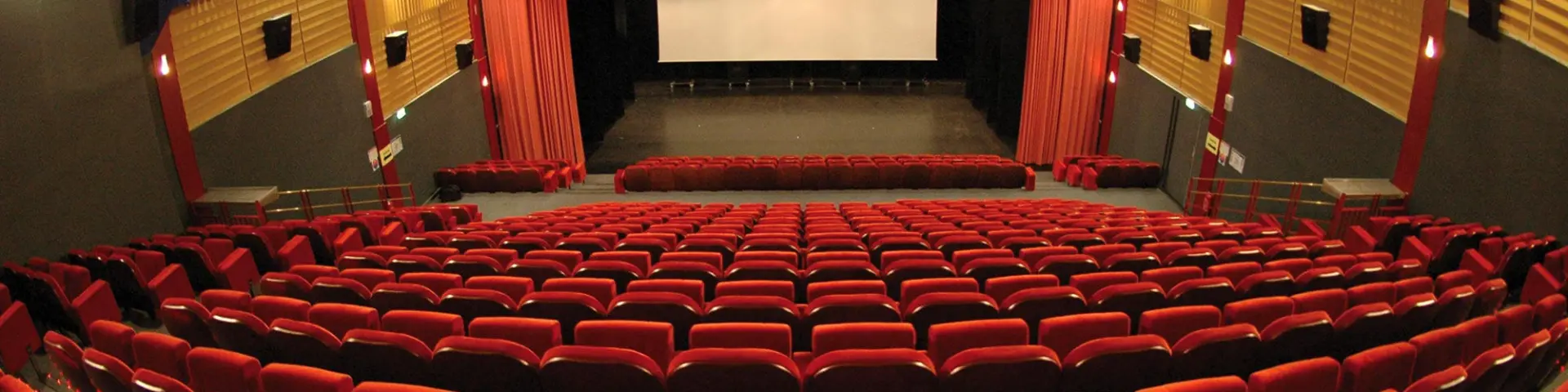 Salle de cinéma avec des sièges rouges et un écran blanc