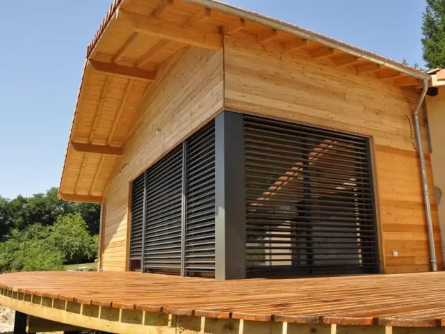 Casa de madera con una gran terraza de madera y contraventanas cerradas