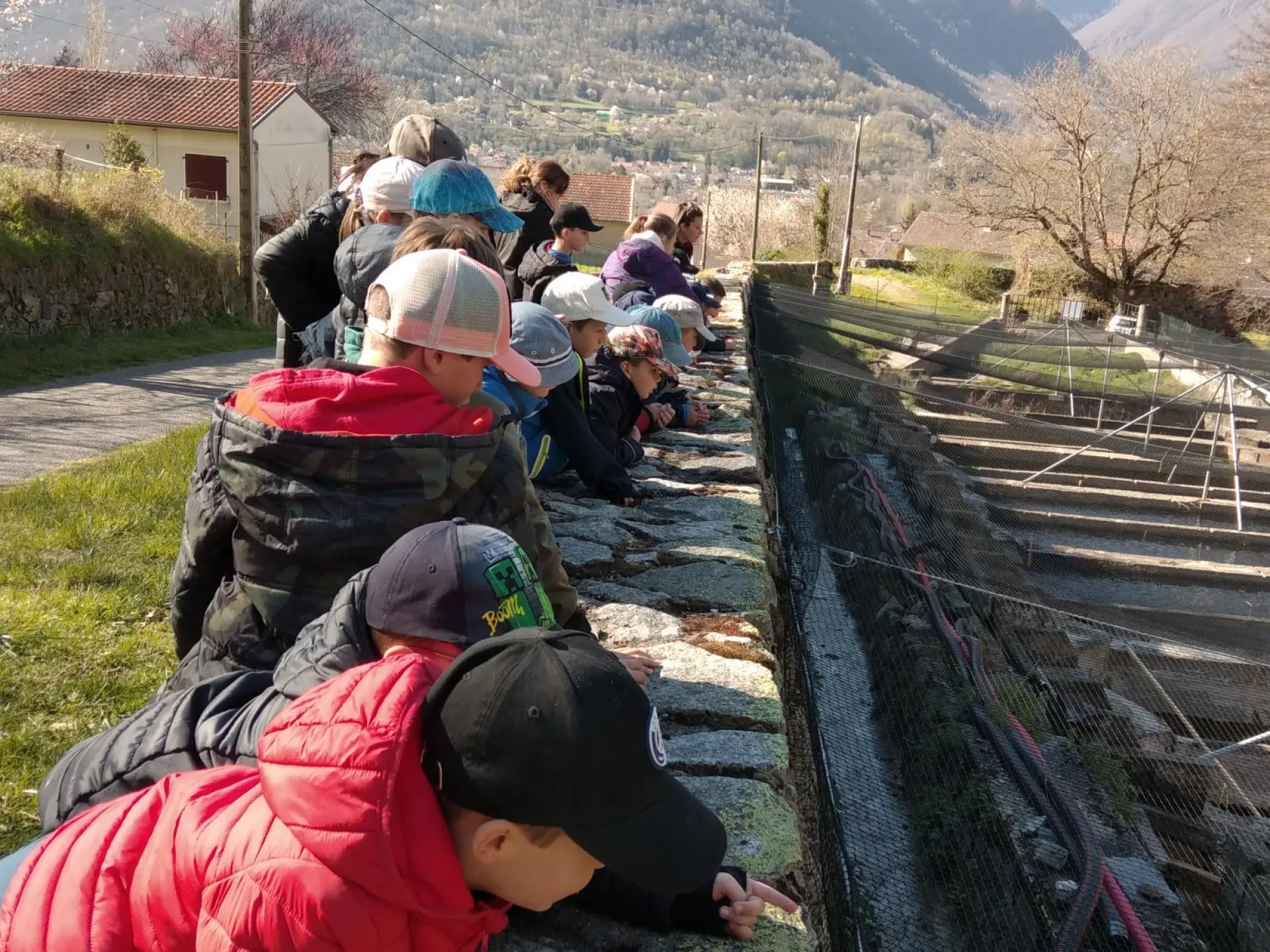 A group of children observing a stone aqueduct