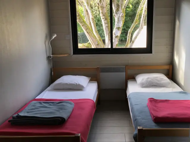 Two single beds in a room with a large window overlooking trees