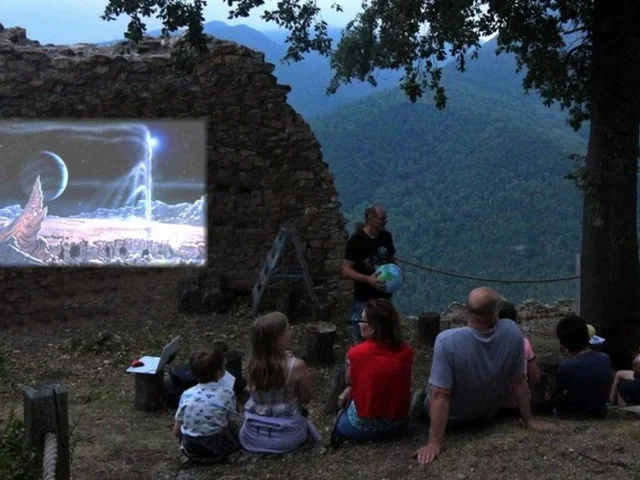Groupe de personnes regardant un film projeté sur un écran en plein air