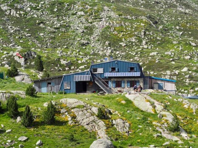 Un refugio de montaña con escaleras y personas afuera