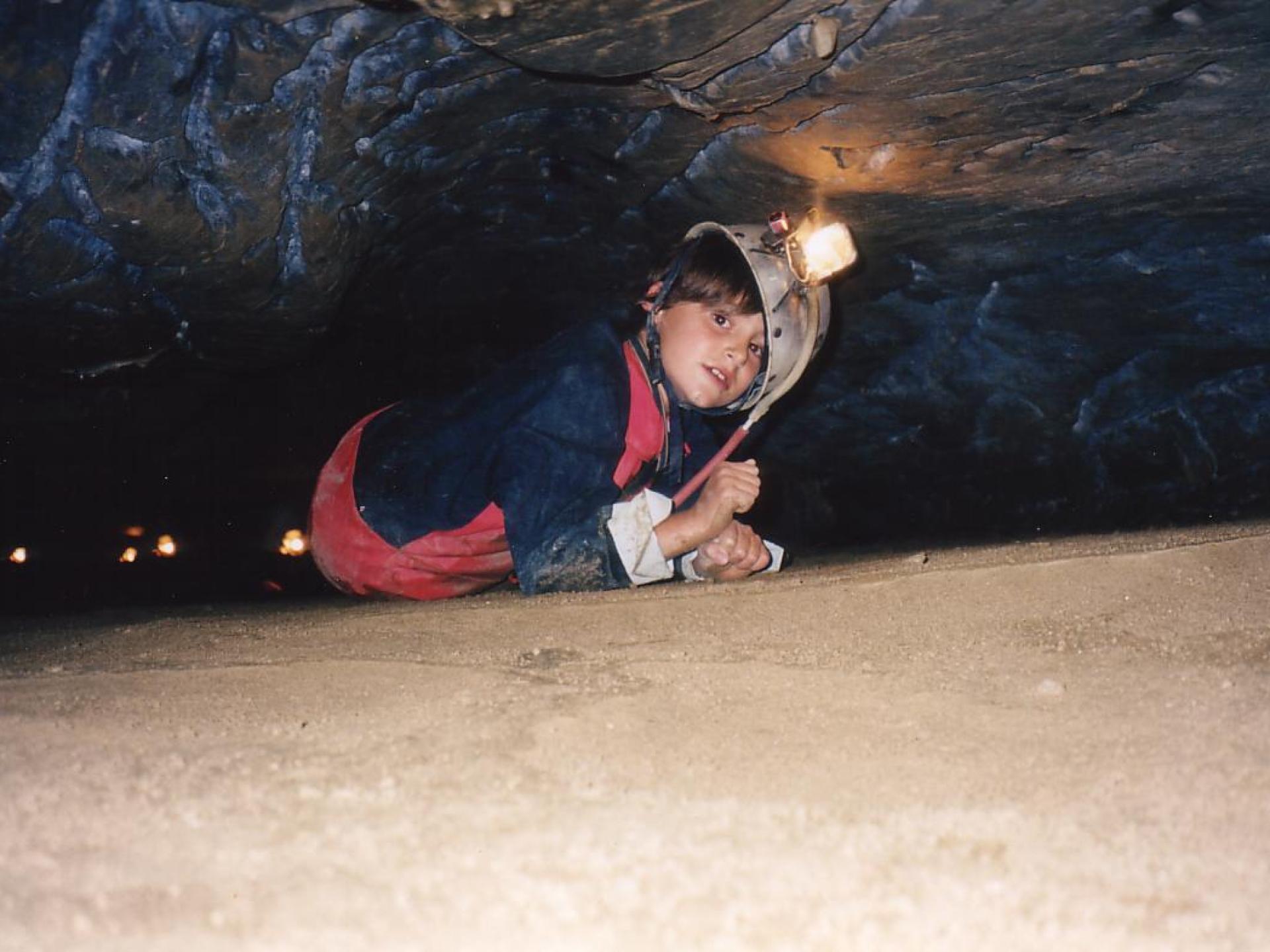 Child exploring a cave with a headlamp