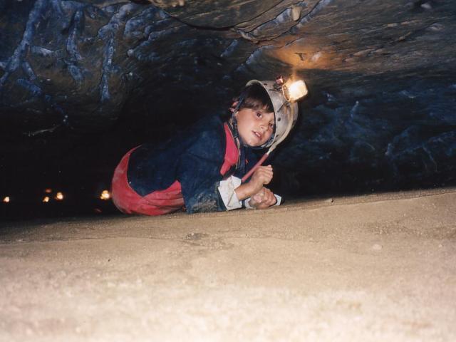 Child exploring a cave with a headlamp
