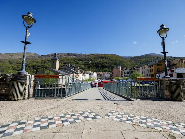 Stone bridge with lampposts and a view of a mountain village