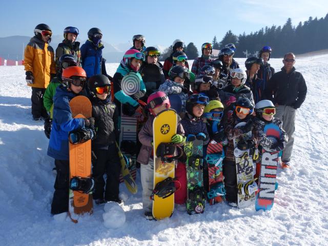 A group of people posing with their snowboards on a snowy slope