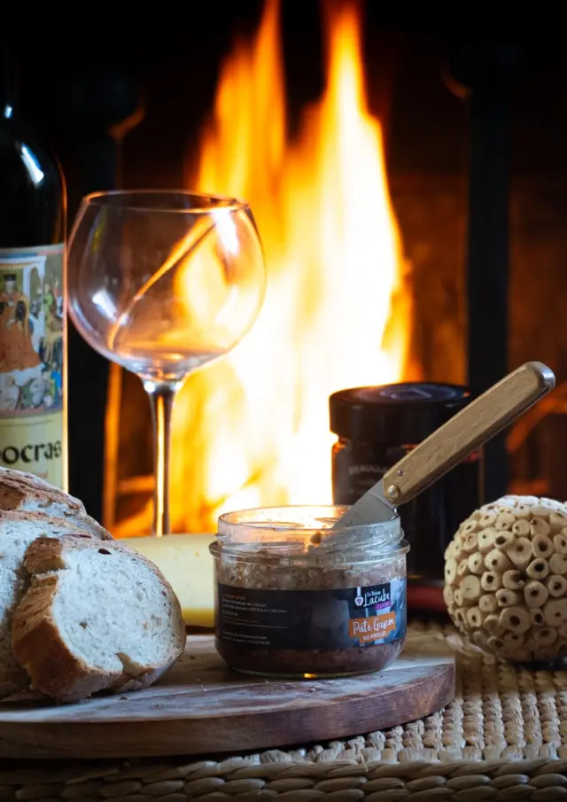 Un plateau avec du pain, du vin, de la bière et des accompagnements devant une cheminée