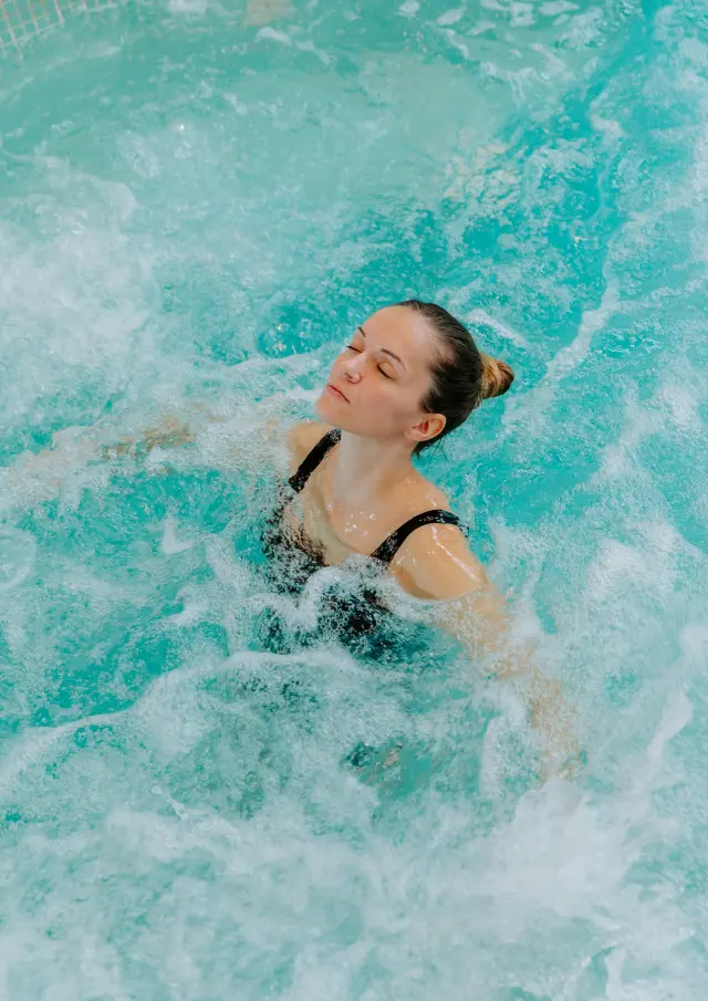 Femme détendue dans un bain à remous avec des bulles