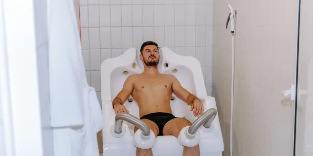 Man sitting in a bathtub with grab bars