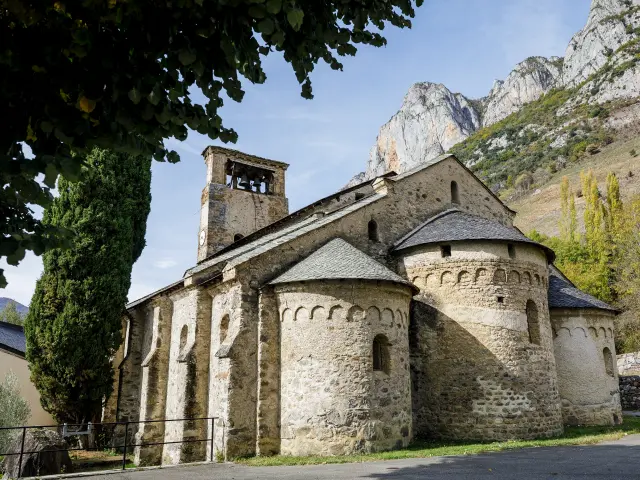 Medieval stone abbey with a tower and Romanesque arches