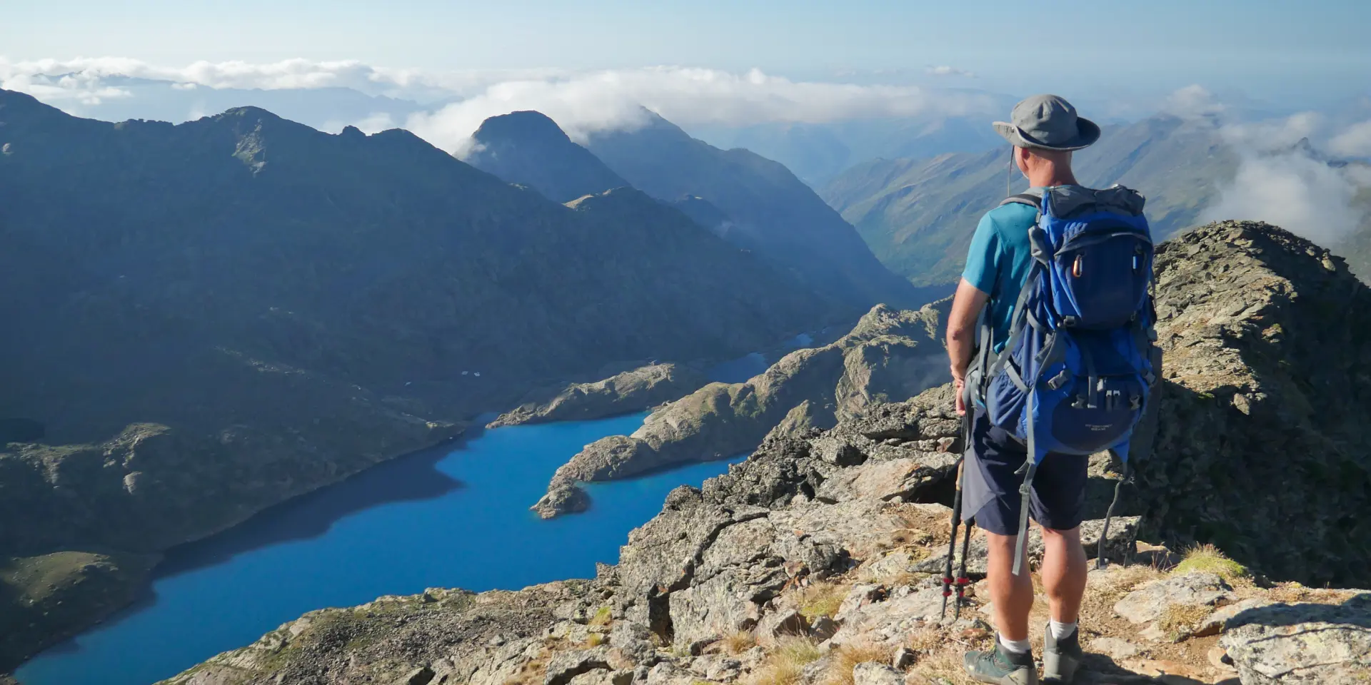Un randonneur avec un sac à dos sur un sentier de montagne avec vue sur un lac