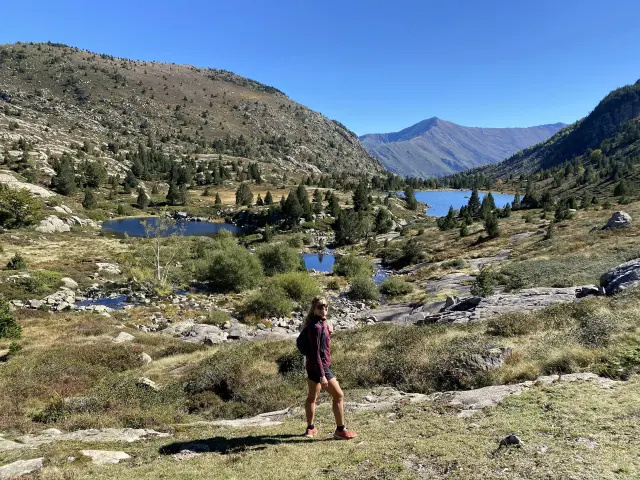 Una persona caminando en un valle montañoso con lagos