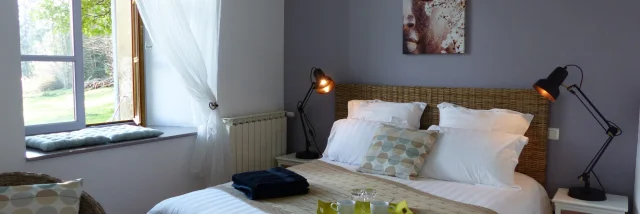 Chambre avec un grand lit, une lampe de chevet, une fenêtre avec vue sur un jardin