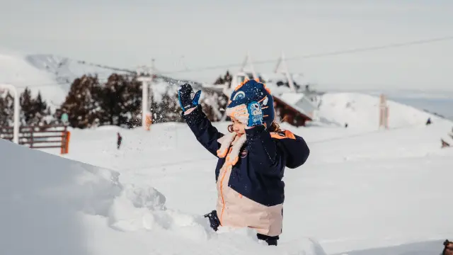 Child dressed warmly playing in the snow with gloves and a scarf