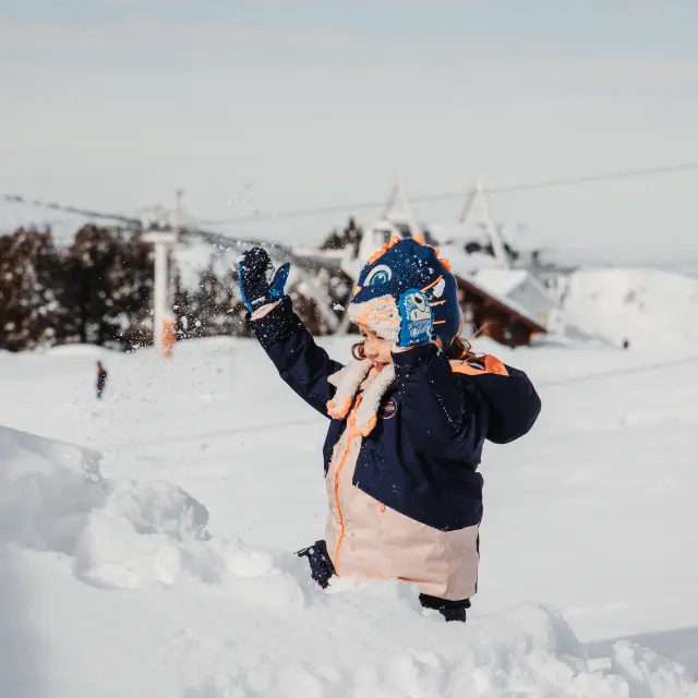 Enfant habillé chaudement jouant dans la neige avec des gants et une écharpe