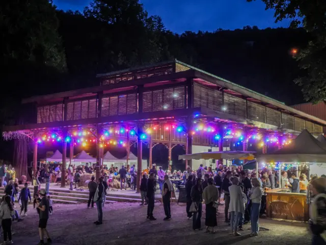 A crowd of people gathered in front of a building decorated with colorful lights