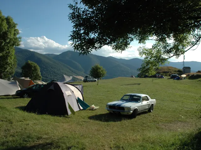 Tent and car in a campsite in the countryside with a mountain view