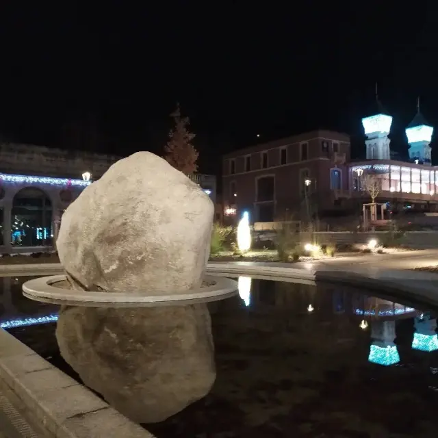 Grande pierre sur une fontaine éclairée la nuit