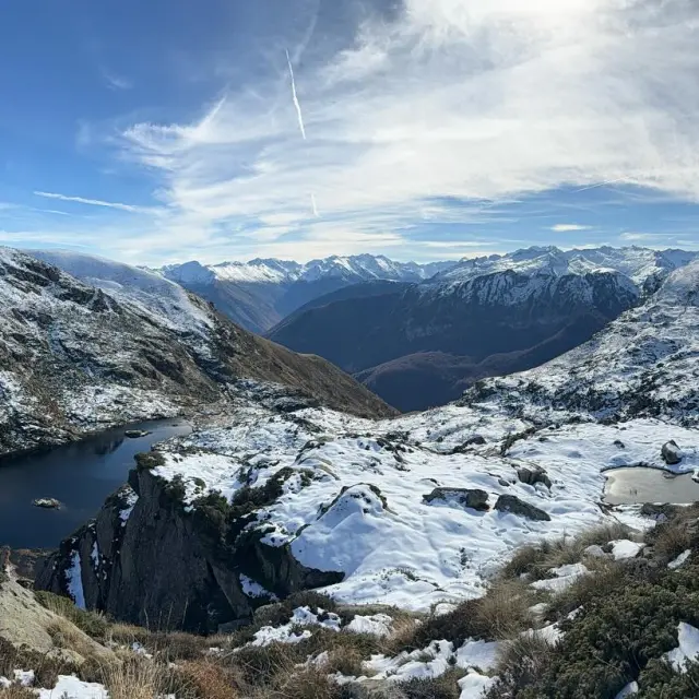 Un lac gelé entouré de montagnes enneigées sous un ciel bleu